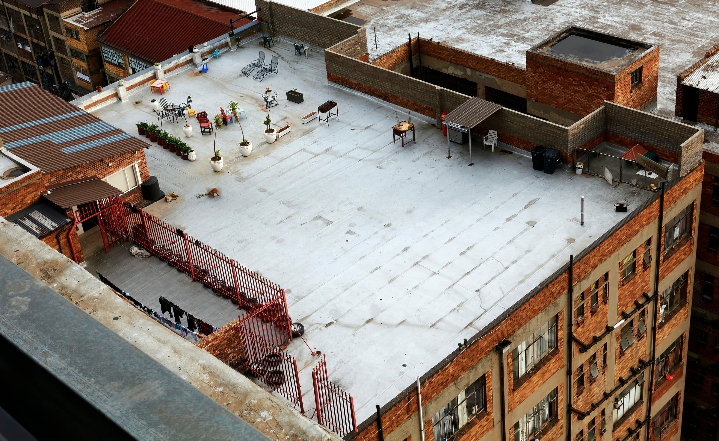 Aerial view of a low-slope roof on a brick building, covered in a light gray coated roll membrane with visible seams
